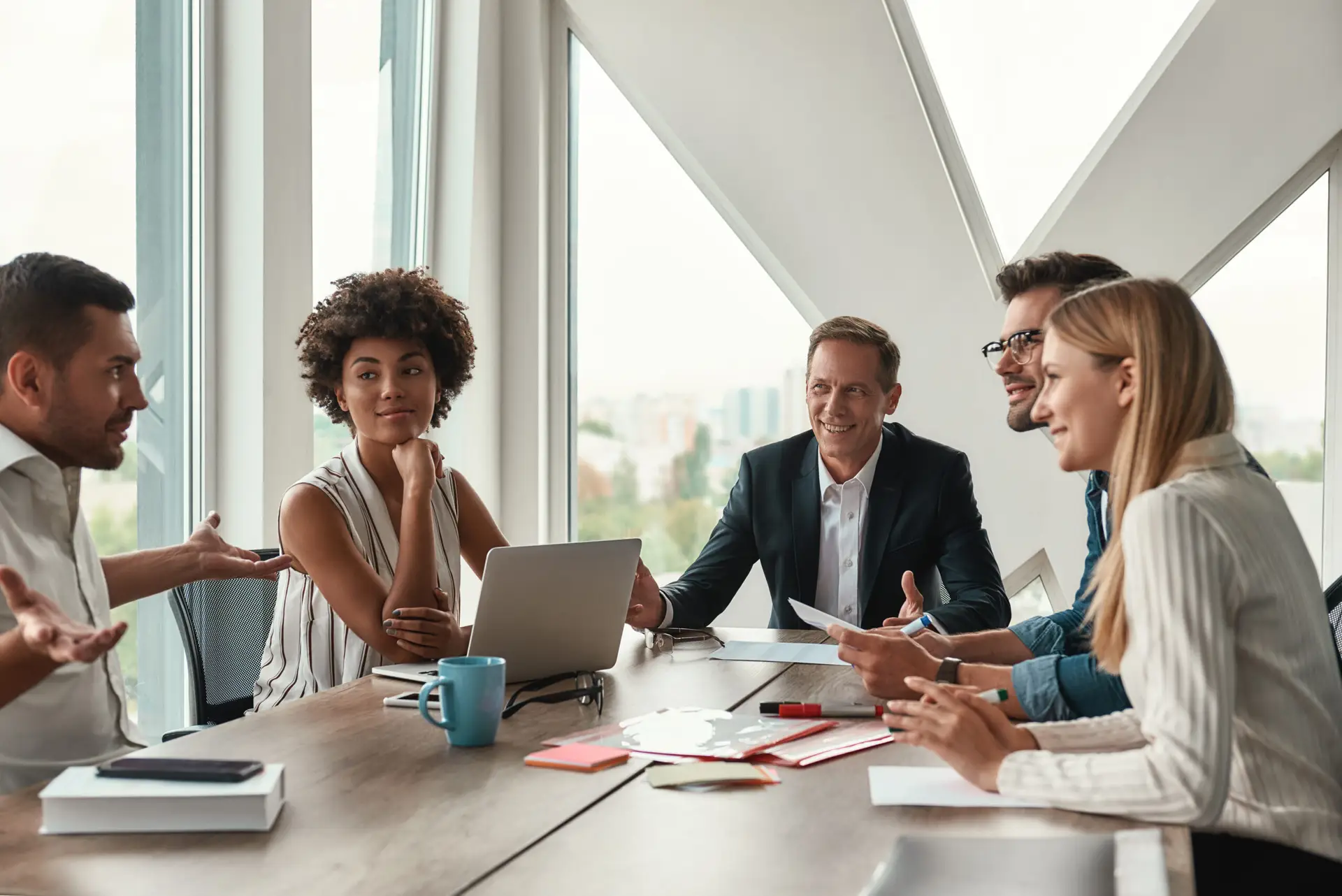 Businesswoman smiling confidently with arms crossed in a modern office setting, symbolizing leadership and success.